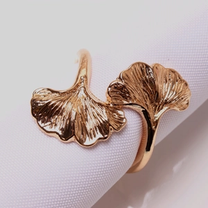 Close-up of golden gingko leaf napkin ring with detailed metal veins on a white fabric