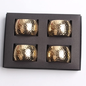 Set of 4 gold hammered metal napkin rings in a black gift box on white background