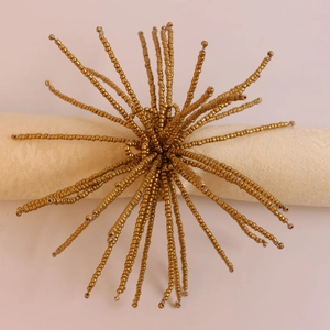 Vue détaillée du rond de serviette perlé doré à la main avec un motif soleil élégant
