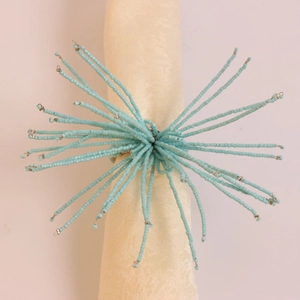 Détail du rond de serviette en perles bleu clair au design étoilé sur serviette beige