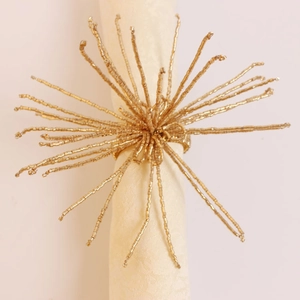 Détail d'un rond de serviette doré en forme d'étoile avec des perles sur une serviette