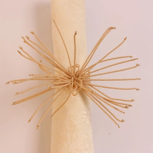 Gros plan sur le rond de serviette en perles artisanales beige avec design soleil tressé