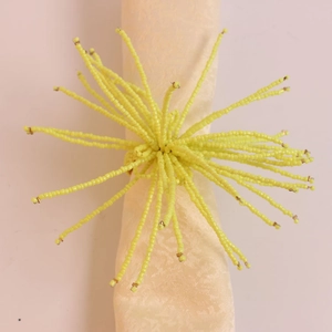 Détail d'un rond de serviette en perles jaunes avec franges au design floral chic