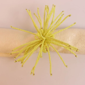 Détail macro du rond de serviette perlé jaune radial sur tissu beige texturé