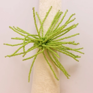 Vue détaillée d'un rond de serviette perlé vert en forme d'étoile sur une serviette