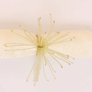 Détail d'un rond de serviette à pompons de perles vert clair avec base dorée