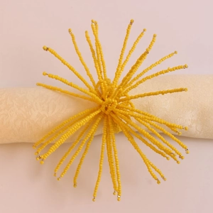 Détail du rond de serviette en perles jaunes avec motif en grappe sur tissu beige