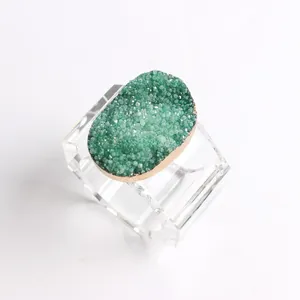 Macro shot of green druzy crystal napkin ring with golden edges and acrylic base