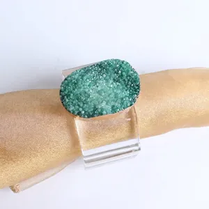 Green crystal cluster napkin ring with transparent acrylic band on gold silk fabric