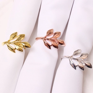 Elegant gold, rose gold and silver leaf napkin rings set on white cloth napkins