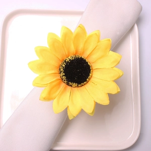 Vibrant yellow sunflower napkin ring with golden fabric petals on a white linen napkin