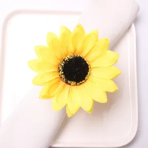 Macro view of sunflower napkin ring with yellow fabric petals on white linen napkin