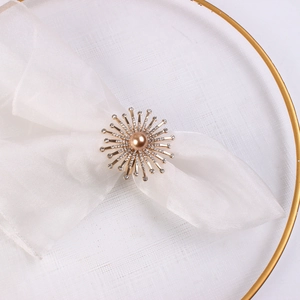 Dettaglio del portatovagliolo a forma di fiore con strass e perla su tessuto bianco