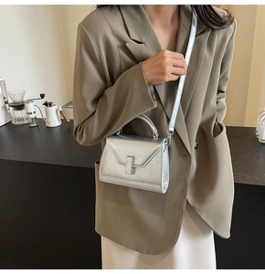 Détail du sac à main argenté métallisé avec bandoulière réglable porté par le mannequin