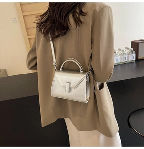 Mini sac bandoulière argenté métallisé avec rabat en V et fermoir porté par le mannequin