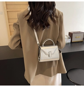 Détail du mini sac carré argenté avec poignée et boucle métallique élégante sur la sangle
