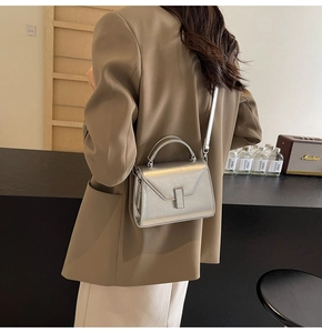 Sac bandoulière argenté métallisé avec rabat en V et fermoir porté par un mannequin