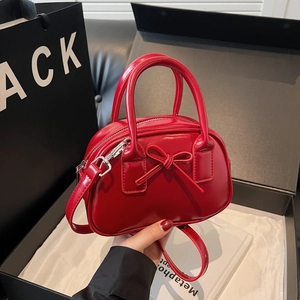 Glossy red mini bowling bag with bow detail and adjustable strap in luxury gift box