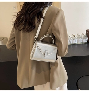 Gros plan d'un petit sac à main argenté porté avec un blazer beige chic et moderne