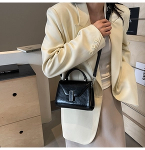 Détail du petit sac carré en cuir ciré noir avec boucle argentée et bandoulière amovible