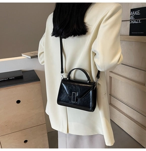 Vue portée d'un sac bandoulière en cuir verni noir avec boucle argentée et bandoulière