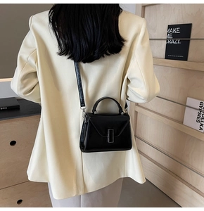 Détail du petit sac à main noir verni porté à l'épaule avec une boucle en métal élégante