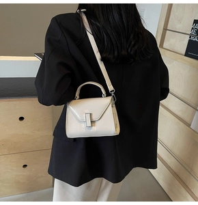 Petit sac bandoulière beige minimaliste avec fermoir argenté porté par un mannequin