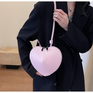 Detalle de mini bolso bandolera rosa en forma de corazón con piel lisa y doble cremallera