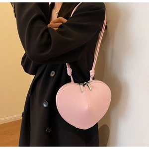 Borsa a tracolla rosa a forma di cuore in ecopelle indossata su un cappotto nero
