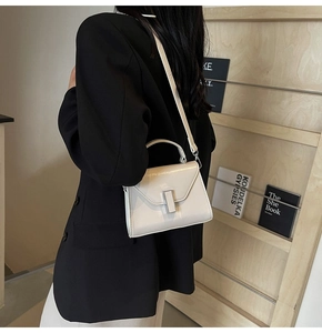 Détail du sac bandoulière blanc cassé avec boucle argentée porté par un mannequin chic
