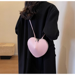 Vista trasera de un bolso bandolera rosa con forma de corazón sobre un abrigo de invierno