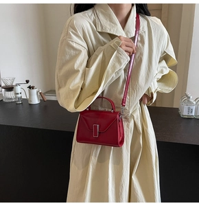 Détail du sac à main rouge en cuir avec boucle argentée porté par un mannequin au café