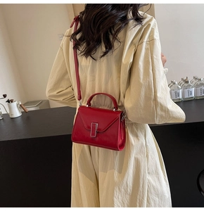 Mini sac à main en cuir verni rouge avec rabat en V et boucle argentée sur modèle