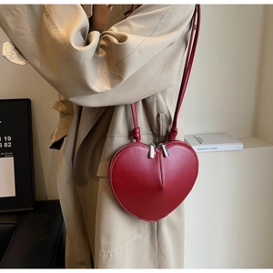 Dettaglio borsa a tracolla a forma di cuore rosso scuro con doppia zip e cinturino in pelle