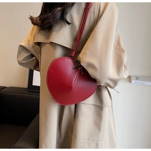 Dettaglio di una borsa a tracolla a cuore in pelle rosso scuro con doppia zip in metallo