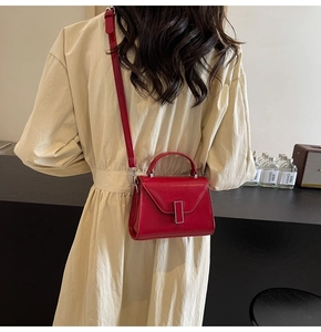 Détail du sac en cuir rouge avec boucle métallique rectangulaire et bandoulière réglable