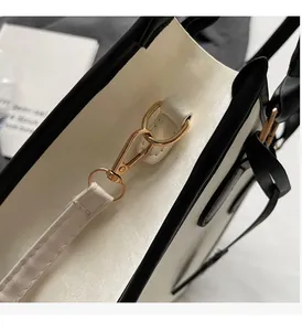 Gros plan sur les attaches métalliques dorées d'un sac cabas en cuir minimaliste