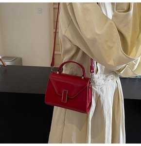 Détail du sac rouge en cuir synthétique avec boucle argentée et poignée ronde