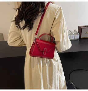 Détail du sac bandoulière en cuir rouge avec boucle argentée et bandoulière réglable