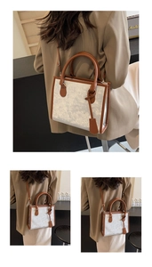 Détail du sac cabas pailleté argenté avec anses brunes porté par un mannequin en costume