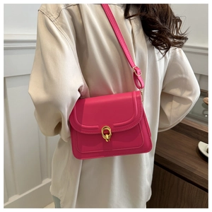 Detailed side view of a rose pink leather crossbody bag with elegant golden ring buckle