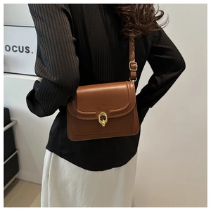 Detail view of brown leather crossbody bag featuring an elegant gold double ring buckle closure