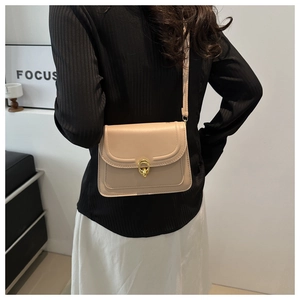 Beige leather crossbody bag with golden buckle buckle shown on a model side view