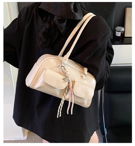 Close-up of creamy white faux leather shoulder bag with star charm and ribbon detail
