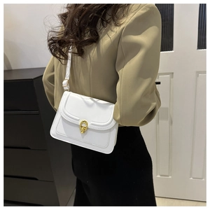 Detail of white crossbody bag featuring a gold horseshoe buckle and adjustable strap