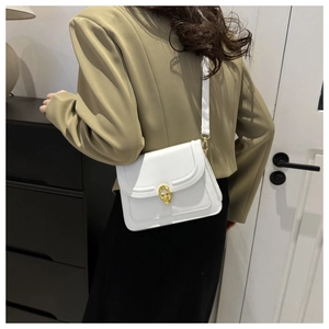 Detailed view of a white leather crossbody bag with an elegant golden horseshoe buckle