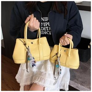 Détail de sacs à main jaunes en cuir grainé avec breloques en deux tailles