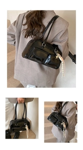 Detail of black glossy patent leather shoulder bag with dual pockets and star charm