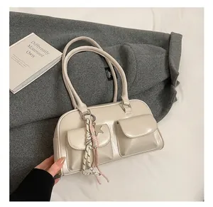 Detail view of cream luxury tote bag with front pockets and star tassel charm