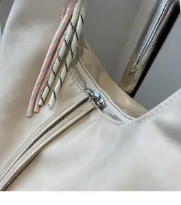 Close-up of beige shoulder bag with smooth silver zipper and colorful braided rope detail